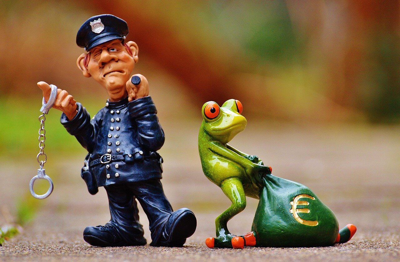 Play figurines of a police man and a frog toting a bag of Euros