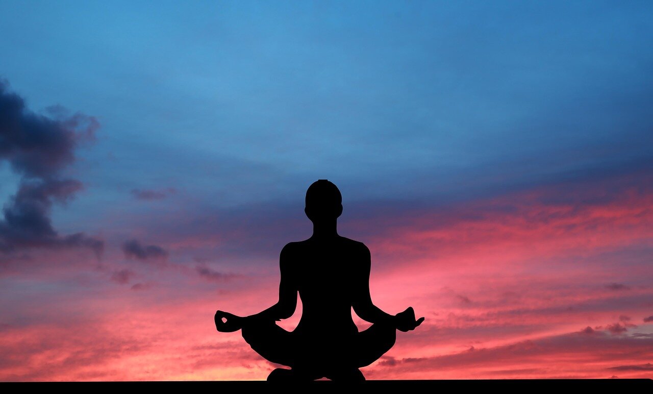 I woman sitting in lotus at sunset
