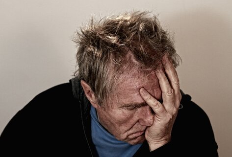 Man sitting with his head in his hand agonizing over something