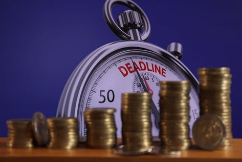 Image of a deadline scale, with coins stacked in front