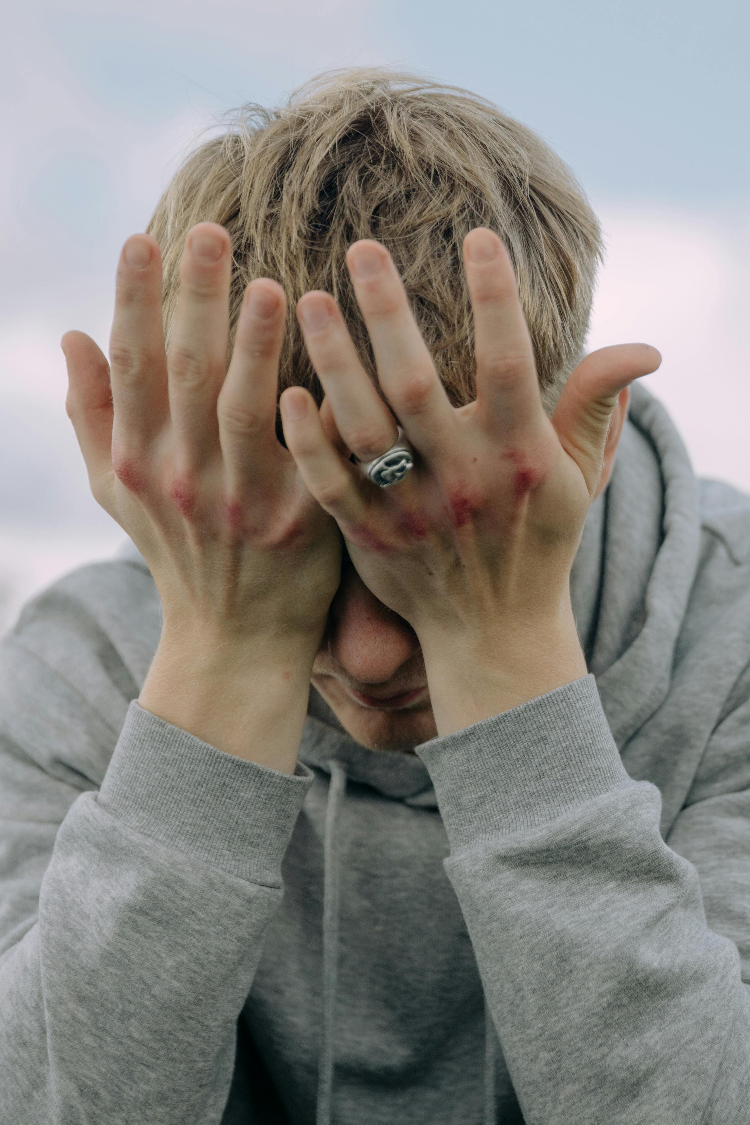 Man wearing a hoodie with his head in his hands in despair