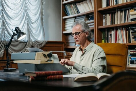 Older man writing behind a desk